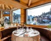 Luxusní restaurace s výhledem na zasněženou krajinu a horskou vesničku.