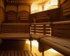Dřevěné lavice s opěradly v sauně s tlumeným osvětlením.