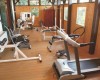 Malá tělocvična s různým fitness vybavením a dřevěnou podlahou.
