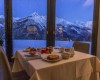 Stůl pro dva s večeří v restauraci s výhledem na zasněžené hory.