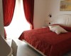 Ložnice s červeným závěsem a přehozem.
