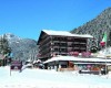 Hotel ve zasněžené horské krajině s italskou vlajkou v popředí.