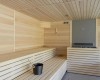Interiér moderní sauny s dřevěnými lavicemi a kovovým vědrem.