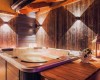 Vnitřní jacuzzi obklopené dřevěnými panely s osvětlením a lucernou na stole.