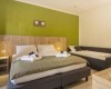 Útulný hotelový pokoj s manželskou postelí, jednolůžkem a zelenou stěnou.