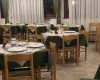 Restaurace se stoly s bílými a zelenými ubrusy připravená na večeři.  
