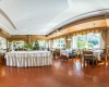 Elegantní restaurace s prostorným uspořádáním stolů a velkými okny s výhledem na přírodu.  