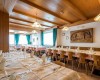 Prostorná restaurace s dřevěným obložením, prostřenými stoly a modrými závěsy.