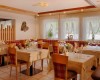 Elegantní restaurace s dřevěnými židlemi a prostřenými stoly u okna s květinami.