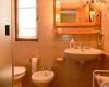 Koupelna se sprchovým koutem, umyvadlem, zrcadlem, bidetem a WC v teplých tónech.  