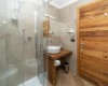 Malá koupelna s proskleným sprchovým koutem a dřevěnými prvky.