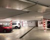 Podzemní parkoviště s auty a sloupy s červeno-bílými pruhy.