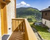 Balkón s výhledem na horskou krajinu s modrou oblohou a oblaky.