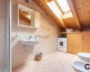 Podkrovní koupelna s umyvadlem, pračkou a střešním oknem.