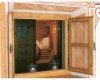 Žena sedící v sauně, pohled přes dřevěné okno.