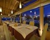 Elegantní restaurace s bílými ubrusy a dřevěným interiérem za soumraku.  