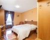 Pokoje s dvoulůžkem, psacím stolem a balkonem, na zdi visí kříž.
