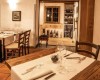 Restaurace s dřevěnými stoly, elegantně prostřenými, a skleněnou vinotékou v pozadí.  