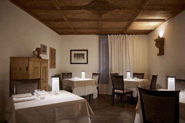 Elegantní restaurace s dřevěným stropem a bílými ubrusy na stolech.