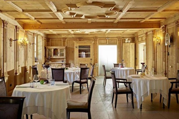 Stylová restaurace s dřevěným obložením a kulatými stoly.