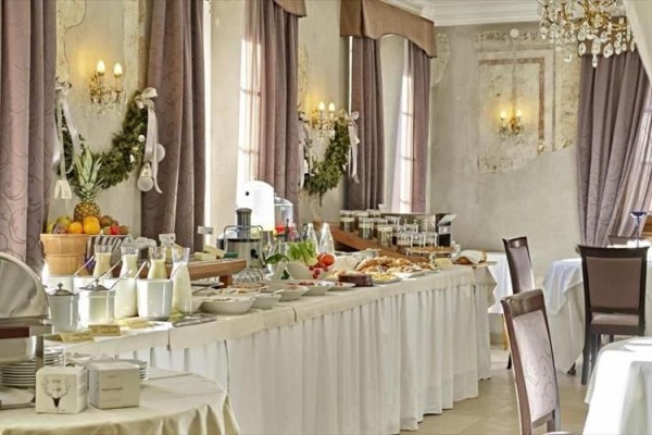 Bufetový stůl s jídlem v elegantní restauraci s křišťálovými lustry a dekorem na zdech.