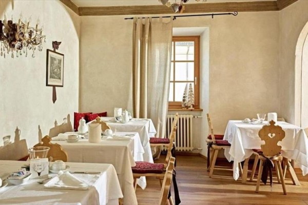 Stylová restaurace s dřevěnými židlemi a bílými prostřenými stoly.