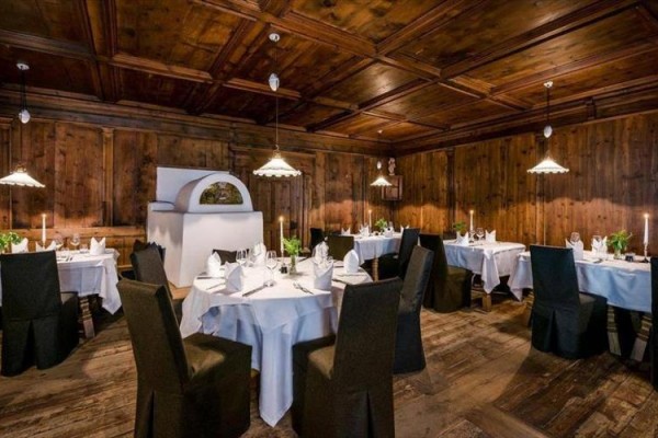 Luxusní restaurace s dřevěným obložením a kulatými stoly s bílými ubrusy.