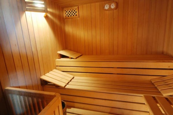 Dřevěná sauna s lavičkami a měřidly na stěně.