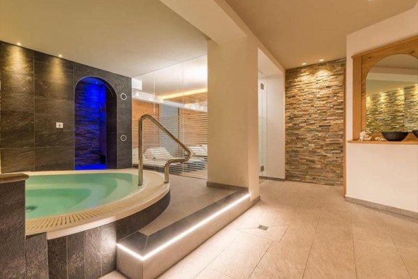 Moderní wellness centrum s vířivkou a kamennými zdmi.