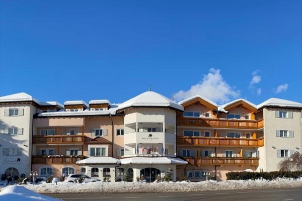 Přední pohled na zasněžený hotel pod modrou oblohou.  