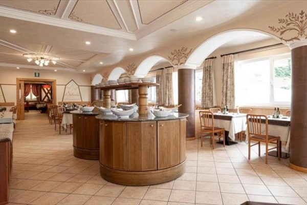 Elegantní restaurace s dřevěnými stoly a bufetovým pultem uprostřed místnosti.  