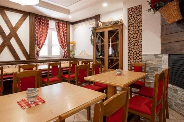Rustikální interiér restaurace s dřevěným nábytkem a červenými doplňky.