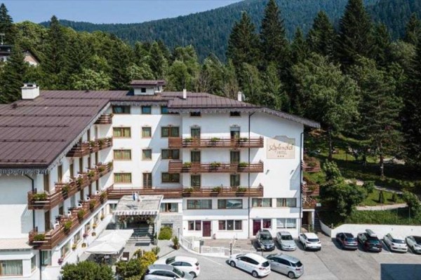 Hotel obklopený lesy s parkovištěm plným aut.