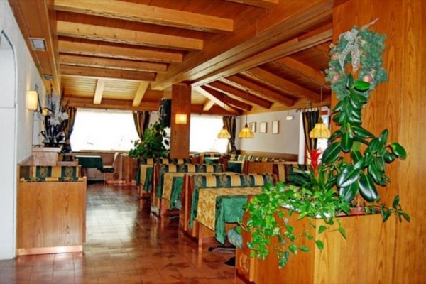 Restaurace s dřevěným interiérem a zelenými rostlinami.  