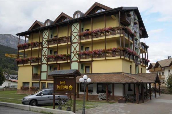 Hotel s dřevěnými balkony plnými květin.