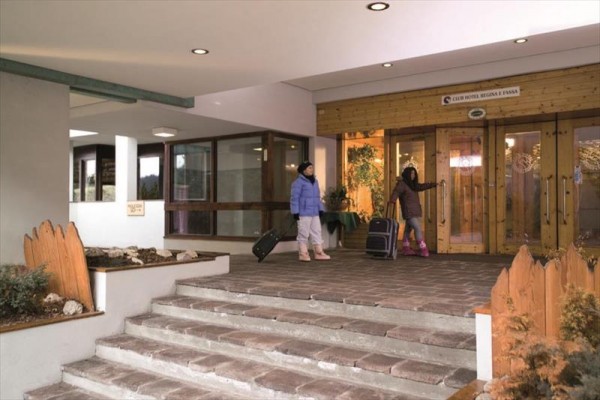 Dvě osoby s kufry před vstupem do hotelu.