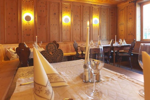 Restaurace s dřevěným obložením, prostřenými stoly a zapálenými svíčkami.