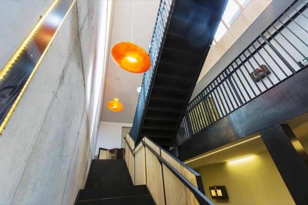 Moderní interiér s černým schodištěm a oranžovými lampami.  