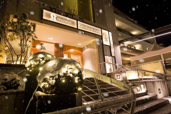 Hlavní vchod do zasněženého hotelu s rozsvícenými vánočními dekoracemi.