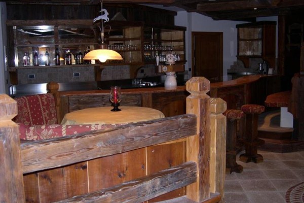 Dřevěný bar s kulatým stolem a židlemi v horském stylu.