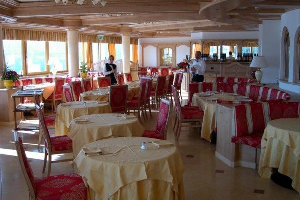 Luxusní restaurace s červenými a zlatými dekoracemi a personálem, který připravuje stoly.