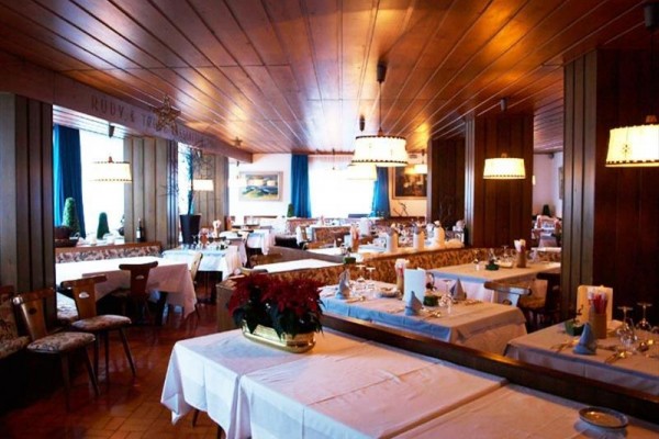 Restaurace s dřevěným obložením a prostřenými stoly.