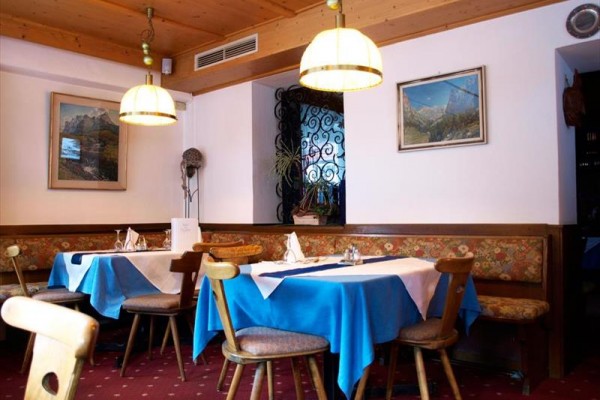 Restaurace s dřevěným nábytkem a modrými ubrusy na stolech.