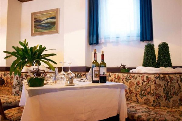 Stůl v restauraci s květinou, víny a prostíráním.