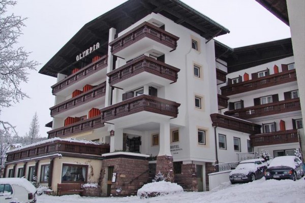 Hotel s dřevěnými balkony pokrytý sněhem.