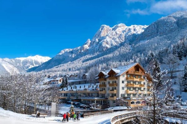 Hotel v zasněžené horské krajině s jasnou modrou oblohou.