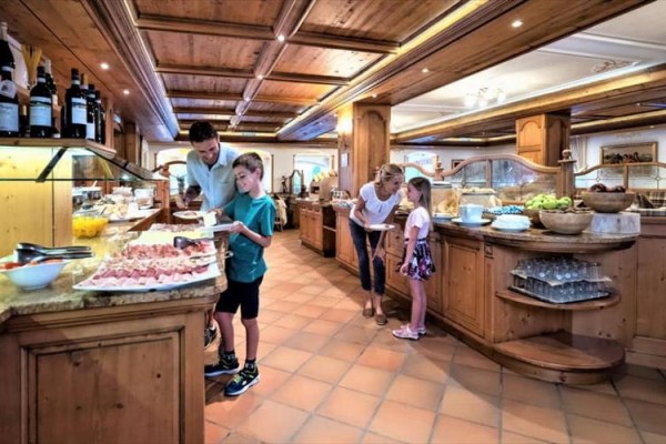 Lidé vybírají jídlo z bufetu v restauraci s dřevěnými prvky.