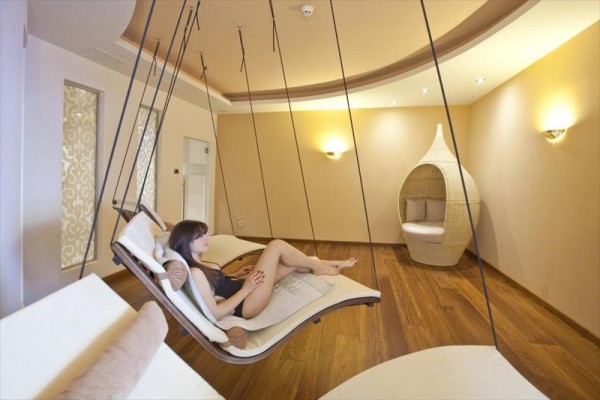 Žena relaxuje na houpacím lehátku v moderním interiéru s dřevěnou podlahou.