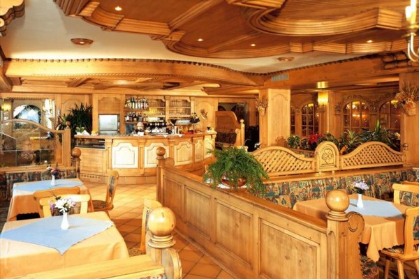 Tradiční restaurace s dřevěným interiérem a látkovými ubrusy na stolech.  