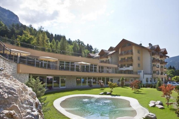Moderní hotel se zahradou a malým jezírkem obklopený lesem.